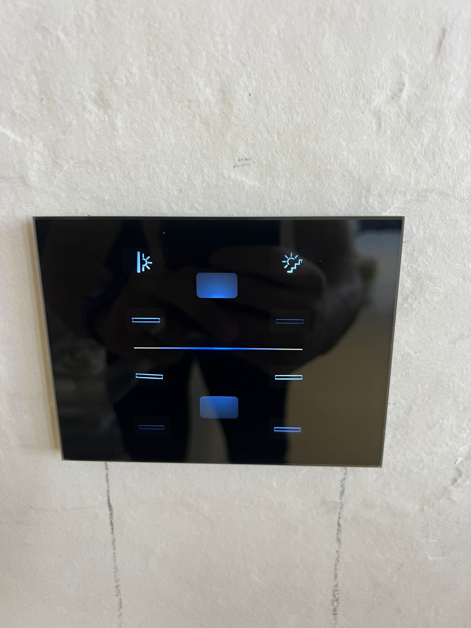 מפסק זכוכית חכם של i-feel על הקיר עם אייקוני תאורה ותריסים מוארים